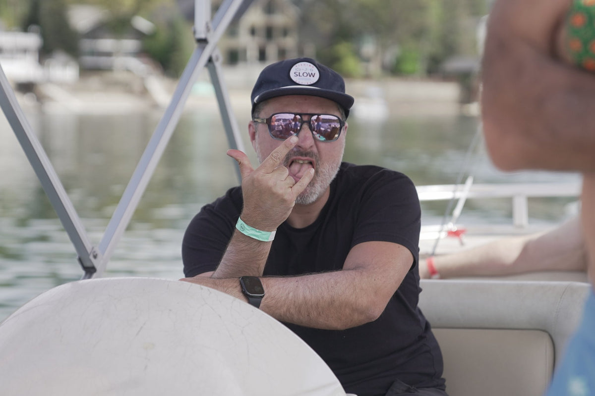 Dark blue Slow Fishing Society hat worn on a boat