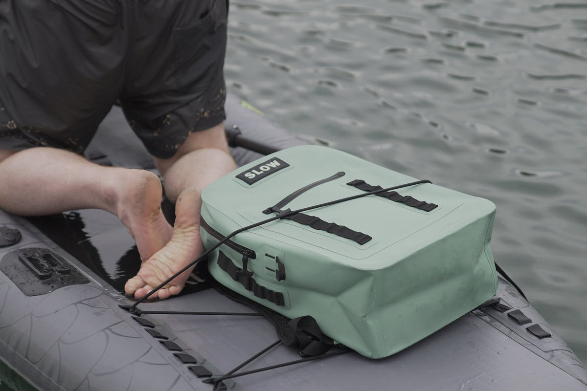 SLOW backpack strapped to a paddleboard on the water